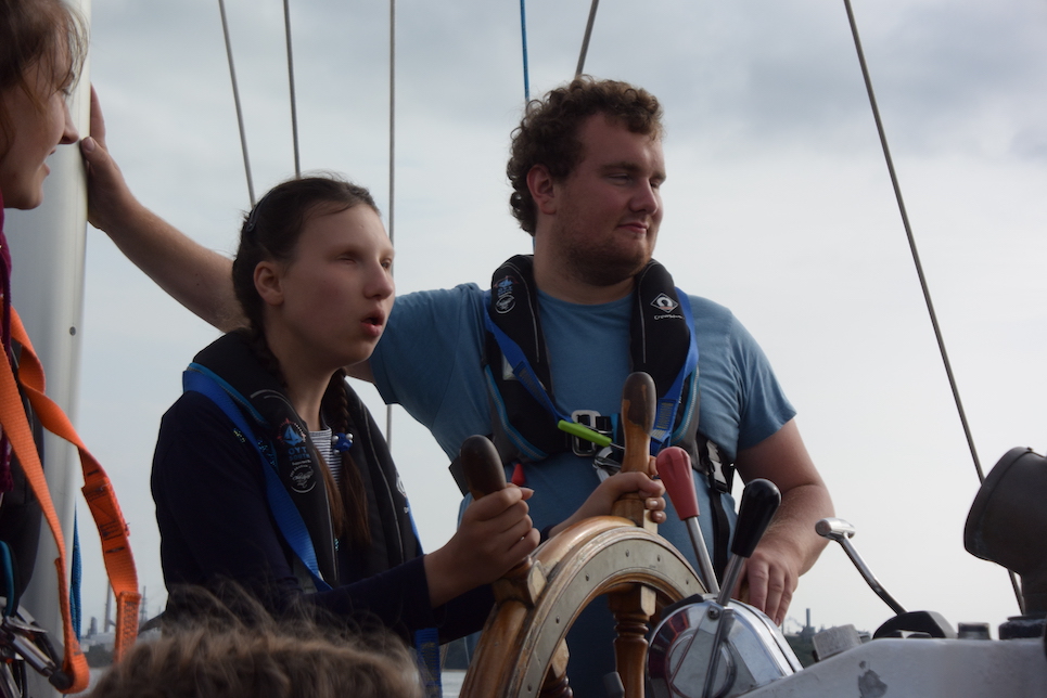 Two Crew Members Manning Helm with Adventure Under Sail